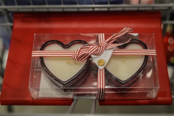 Two Valentines red heart candles in background of decorating store interior