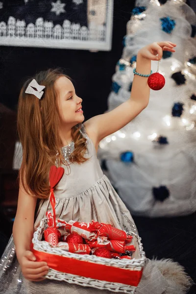 Little girl holds a basket of sweets and Christmas ball. The con