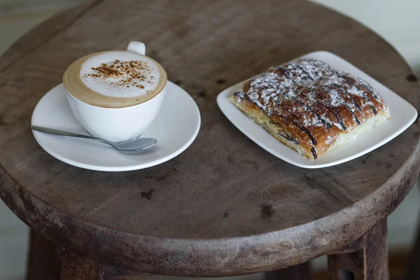 Aroma cappuccino with chocolate croissant on the round vintage wooden table