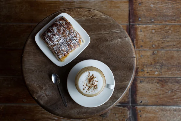 Aroma cappuccino with chocolate croissant on the round vintage wooden table