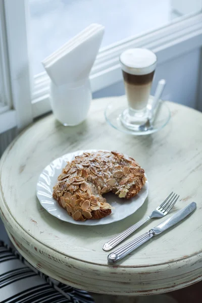 Delicious almond croissant on vintage white table with hot coffee latte