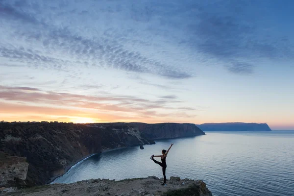 Woman practicing yoga near sea