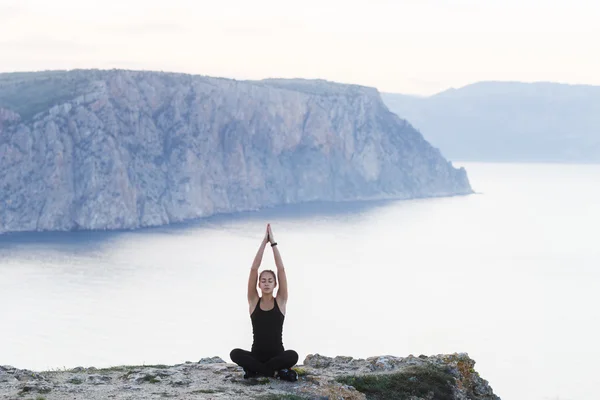 Woman practicing yoga near sea