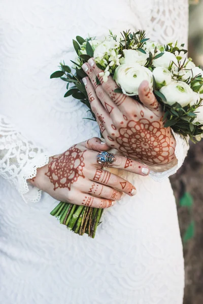 Bouquet in bride\'s hands with mehendi tattoo