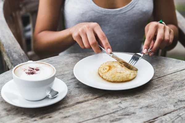 Woman eating breakfast with banana pancake