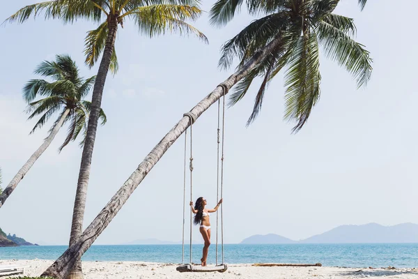 Woman swinging on on paradise beach