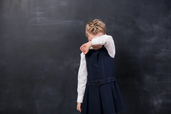Offended schoolgirl stands at the blackboard