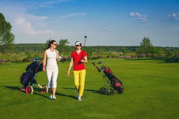 Two pretty women golfers walking at golf course