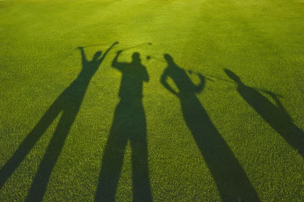 Four golfers silhouette on grass