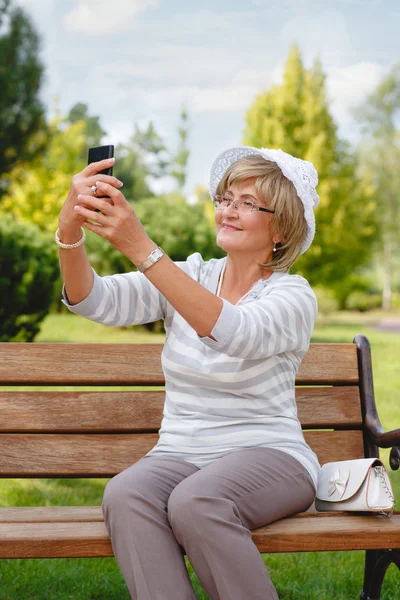 Attractive mature woman using smartphone in a park .