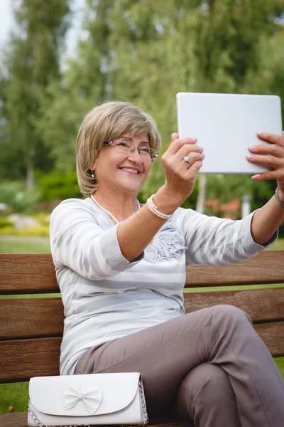 Attractive mature woman using digital tablet in a park