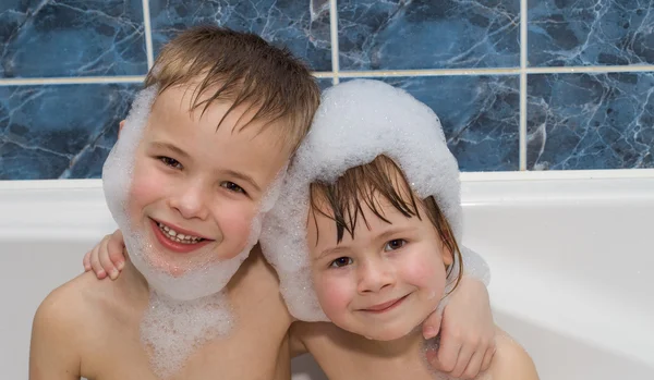 Two little childrewn in a bathtub with shampoo foam