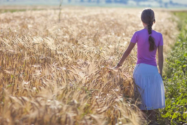 Young woman with long brown hair standing in wheat field. Unity