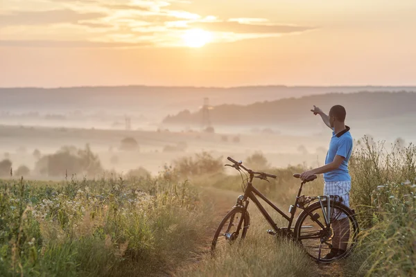 Young man standing near  bicycle in morning sunrise with wonderf