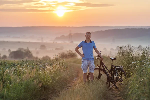 Young man standing near  bicycle in morning sunrise with wonderf