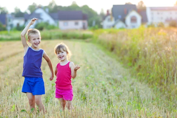 Little girl and boy standind on field with golden sunlight