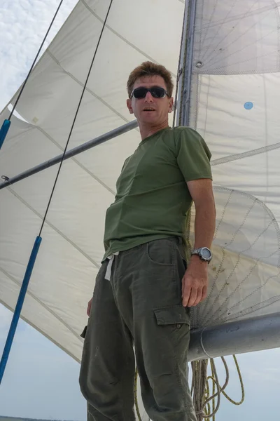 A successful man standing on a yacht under sail.