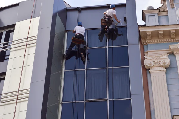 Two Workers cleaning windows service on high rise building