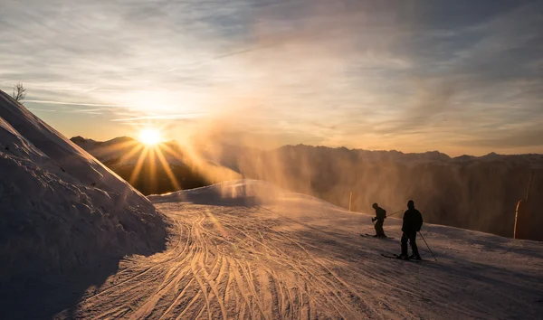 Skiers on the piste at dusk