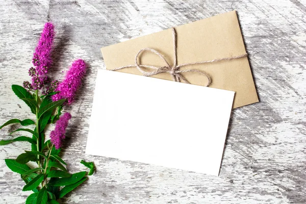 Blank white greeting card and envelope with purple wildflowers