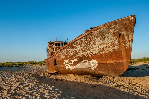 The rusty ship is on the sand