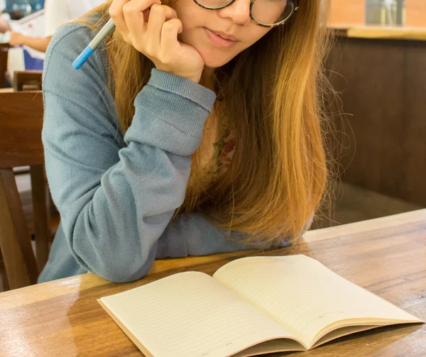 Asian woman thinking what to write on notebook