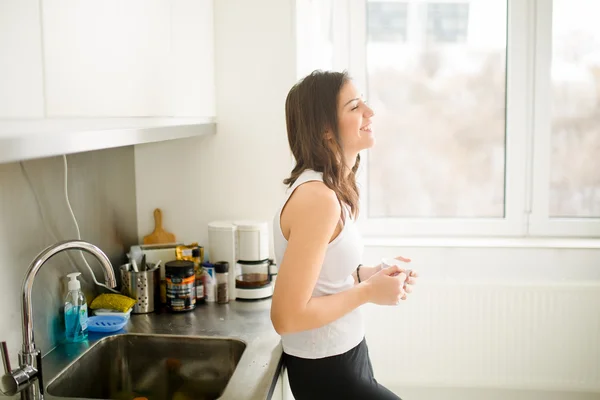 Modern working woman lifestyle-drinking coffee or tea in the morning in the kitchen,starting your day.Positive energy and emotion.Productivity,happiness,enjoyment,determination concept