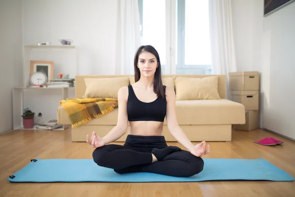 Meditation.Healthy living.Living room for after work relaxation and exercise.Lotus pose,practicing yoga and pilates in small improvised home space.Exercise that you can do at home.