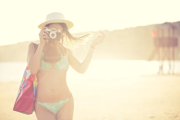 Attractive fit trendy modern hipster woman taking photos with retro vintage film camera.Lifestyle photographer.Summer beach woman taking picture during summer holiday vacation travel
