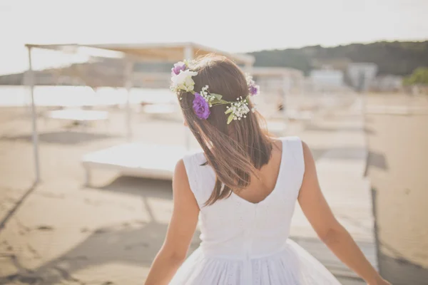 Summer beach fashion woman enjoying summer and sun, walking the beach near clear blue sea. Concept of summer feeling, freedom, happiness. Fit and healthy summer body flower hat