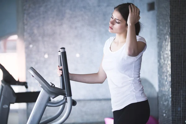 Fitness girl is working out with stepper.Strong brunette with curly hair doing aerobics on stepper.Strong young girl exercising on stepper.Woman doing fitness exercises on stepper at gymnasium