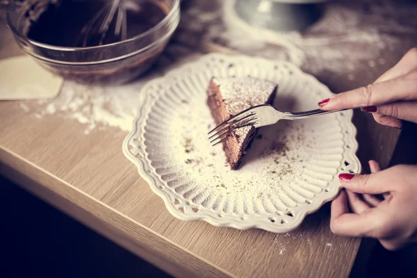 Dark chocolate cake with icing powdered sugar on top served on a cute little vintage ceramic plate.Homemade chocolate cake served with mess in the background of making the cake.Calories and sugars