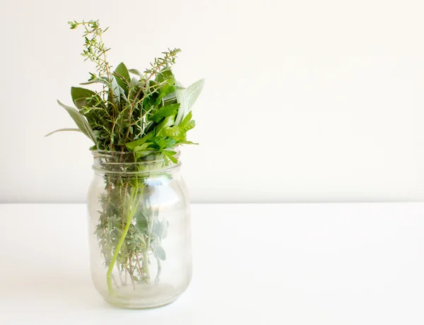 Herbs in glass jar on table