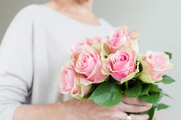 Older woman holding roses (cropped)