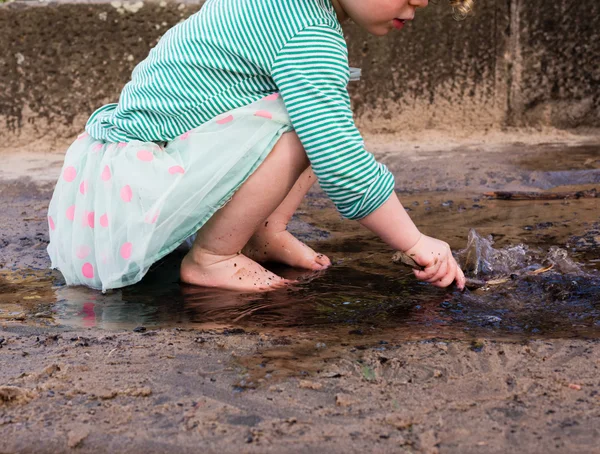 Toddler playing with stick in water