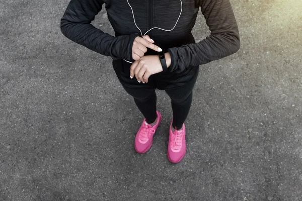Unrecognizable cropped female in sportswear wearing a fitness tracker on her wrist outdoors