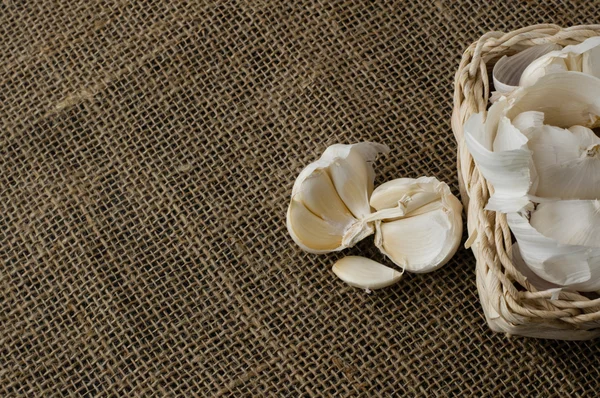 Garlic cloves in a small basket on jute tablecloth