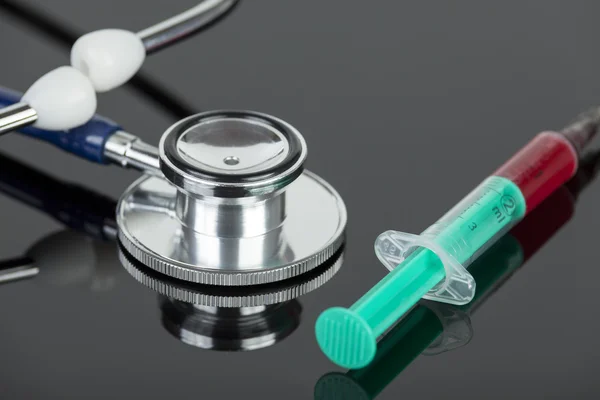 Blood filled hypodermic needle with stethoscope on lab table