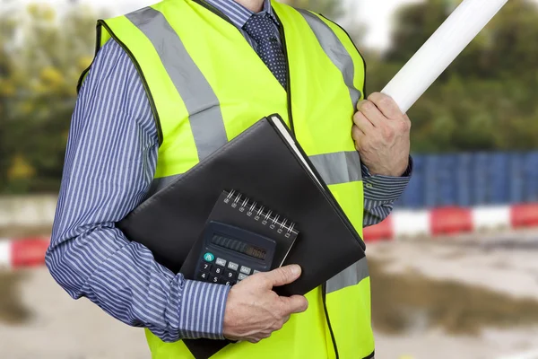 Building surveyor in high visibility carrying work folders