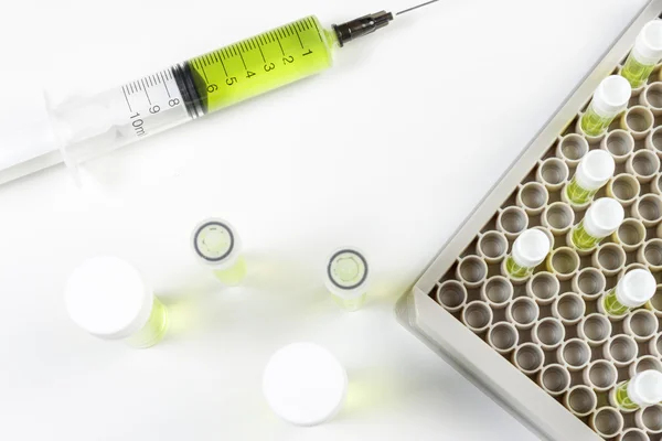 Above view of syringe and vials containing green liquid