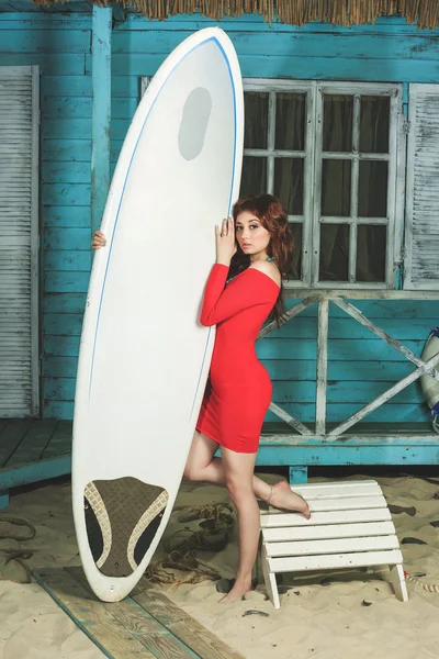 Red-haired girl on the beach with surfboard