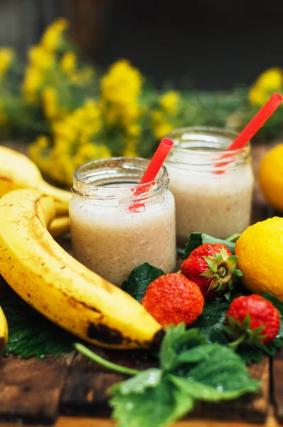 Fruit Smoothies. banana smoothies with milk. Banana Smoothie on a wooden table. Healthy breakfast: banana smoothie with oatmeal. Banana smoothie in glass with fresh fruits on wooden background
