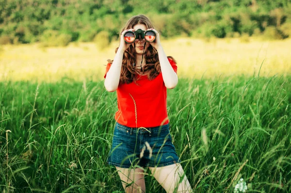 Girl in a red  looking through binoculars. woman looking through