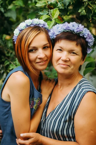 Portrait of a smiling mother and daughter are posing in wreaths