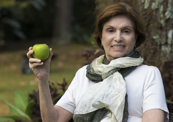 Senior Woman Holding a Fresh Apple in a Garden