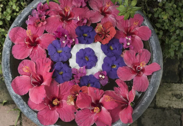 Floating hibiscus flowers on a round bowl filled with water