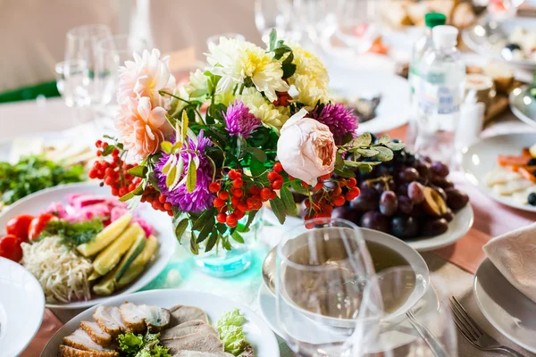Beautifully decorated banquet table with flowers and different food snacks and appetizers with sandwich, wine glass, plate, apple on corporate event or wedding celebration