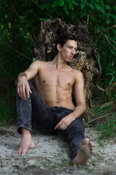 Young man sitting sand posing skinny slim fit abs