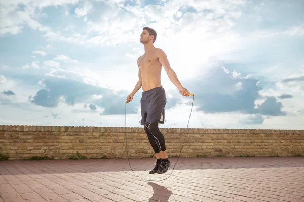 Young man jump jumping rope fit slim abs model sunny sky
