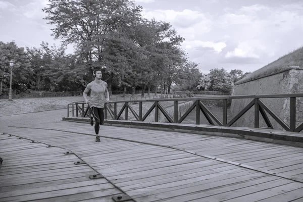 Young man running jogging  outdoors nature bridge